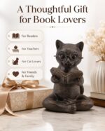 Bronze resin figurine of a cat with glasses, sitting cross-legged and reading an open book, on a light surface.