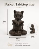 Bronze resin figurine of a cat with glasses, sitting cross-legged and reading an open book, on a light surface.