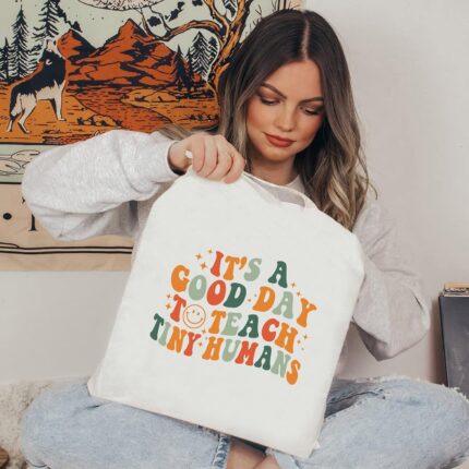 Kimoli Teacher Appreciation Canvas Tote Bag with a design suitable for educators, shown in a natural setting.