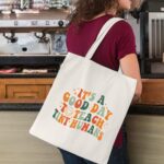 Kimoli Teacher Appreciation Canvas Tote Bag with a design suitable for educators, shown in a natural setting.