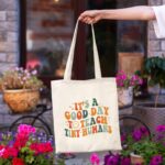 Kimoli Teacher Appreciation Canvas Tote Bag with a design suitable for educators, shown in a natural setting.